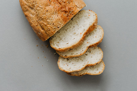 Slices bread with loaf bread on gray  top view