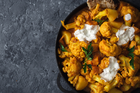 Vegetarian asian food. Cauliflower curry on a dark stone  with copy space top view. Healthy and tasty food conceptの写真素材