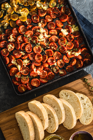 Baked juicy cherry tomatoes into a baking tray on dark  top viewの写真素材