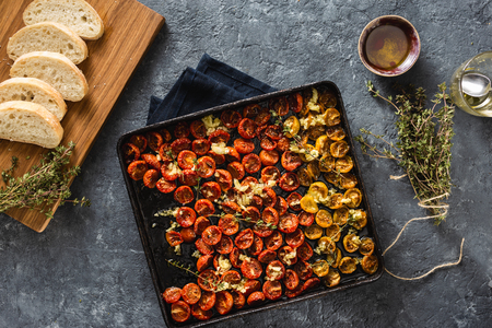 Red baked cherry tomatoes in baking tray top viewの写真素材