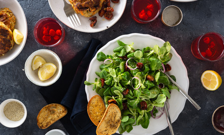 Dinner table with bowl green salad and cutlets. Rustic style