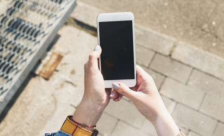 Female hands holding a smartphone with a blank screenの写真素材