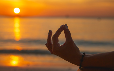 Adult woman do meditation on the ocean beach at sunset Â close upの写真素材
