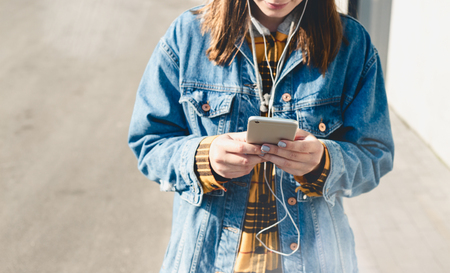 Happy young woman using social media on their smartphones walking down a city streetの写真素材