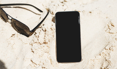 Smartphone with blank screen on the beach in summerの写真素材