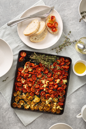 Red baked cherry tomatoes into baking tray on concrete background top viewの写真素材