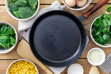 Empty cooking pan with ingredients for cooking healthy breakfast eggs with broccoli, spinach and cheese on wooden table top viewの写真素材
