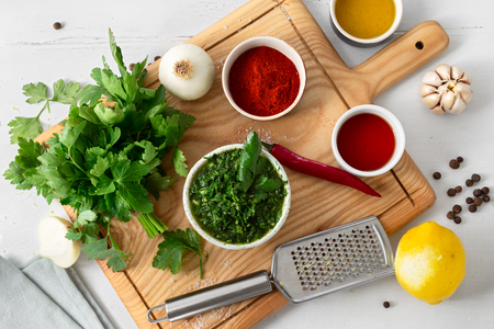 Raw ingredients for preparation Argentinian green Chimichurri or Chimmichurri salsa or sauce on white wooden tableの写真素材