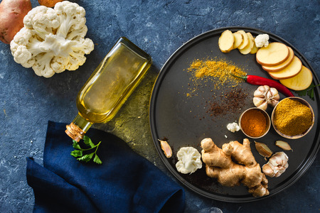 Set raw ingredients cooking vegetarian Indian food aloo gobi on dark stoneの写真素材