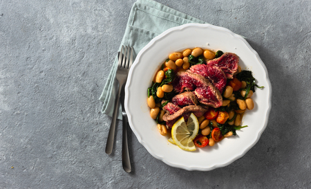 Dinner plate with beef steak, white beans, spinach and tomatoes top view with copy spaceの写真素材