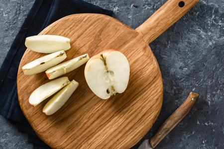 Ripe apple slices on wooden cutting board top viewの写真素材