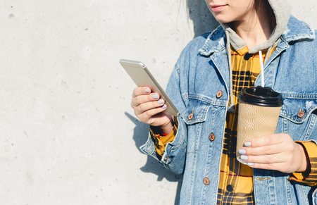 Young female using his smartphone on the street. Woman texting on her phoneの写真素材
