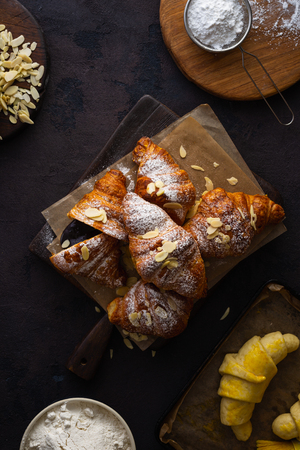 Fresh croissants with almond flakes and icing sugar top viewの写真素材
