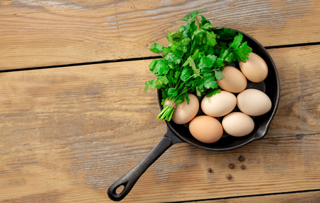 Fresh raw homemade chicken brown eggs in a frying pan on a wooden table. Top viewの写真素材