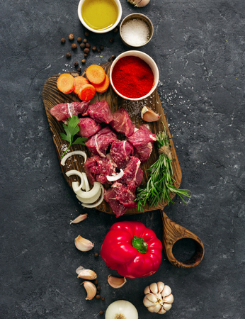Sliced beef fillet with vegetable. kitchen table with Ñuts meat and veggies on dark table top view. Ingredients cooking meatの写真素材