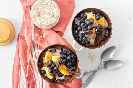 Breakfast table with plate oatmeal with fried banana, chocolate and blueberry on a white background top viewの写真素材