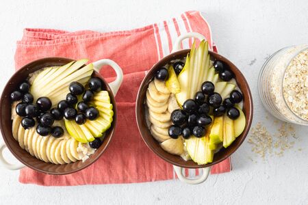 Healthy breakfast table concept. Plate with oatmeal and pear, apple, blueberry, banana on a white background top viewの写真素材