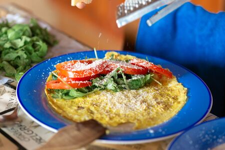 Healthy breakfast. Omelet with tomatoes and arugula on a plate in the home kitchenの写真素材
