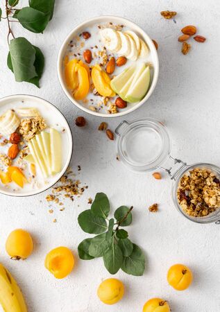 Granola breakfast with fruits, nuts, milk and peanut butter in bowl on a white background. Healthy breakfast cereal top viewの写真素材