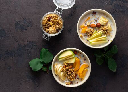 Granola breakfast with fruits, nuts, milk and peanut butter in bowl on a white background. Healthy breakfast cereal top viewの写真素材