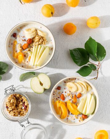 Granola breakfast with fruits, nuts, milk and peanut butter in bowl on a white background. Healthy breakfast cereal top viewの写真素材