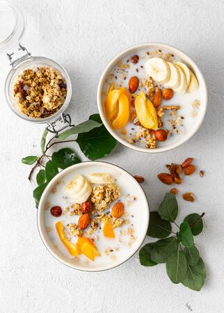 Granola cereal with fruits, nuts, milk and peanut butter in bowl on a white background. Healthy breakfast cereal top viewの写真素材