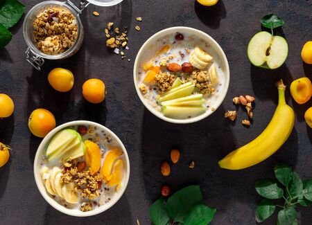 Granola cereal with fruits, nuts, milk and peanut butter in bowl on a white background. Healthy breakfast cereal top viewの写真素材