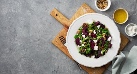 Fresh summer salad with grilled beets, feta cheese and nuts on a dark background top viewの写真素材