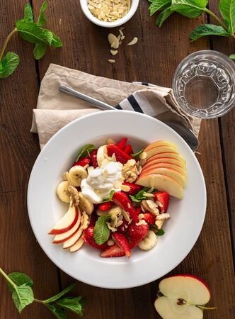 Fruit salad bowl on a wooden table top view. Healthy summer foodの写真素材