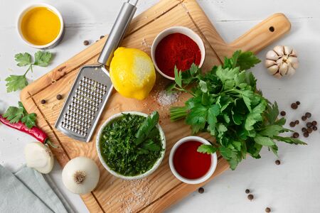 Top view cooking background. Raw ingredients for cooking green Chimichurri or Chimmichurri salsa or sauce on white wooden tableの写真素材
