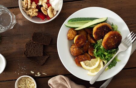 Plate of food. Fresh vegetarian cutlets with new potatoes and salad on a wooden table top viewの写真素材