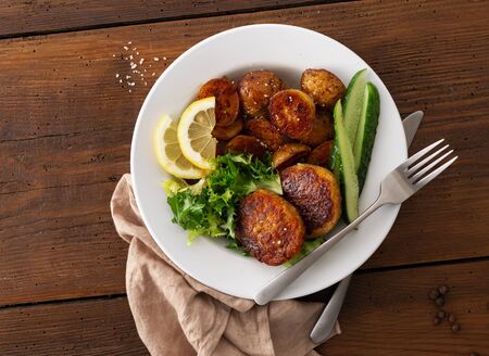 Plate of food. Fresh vegetarian cutlets with new potatoes and salad on a wooden table top viewの写真素材