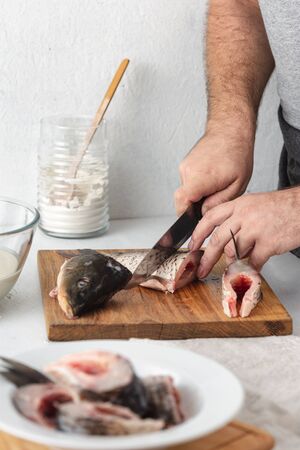 Man prepares carp river fish in home kitchen. Cooking healthy and diet foodの写真素材