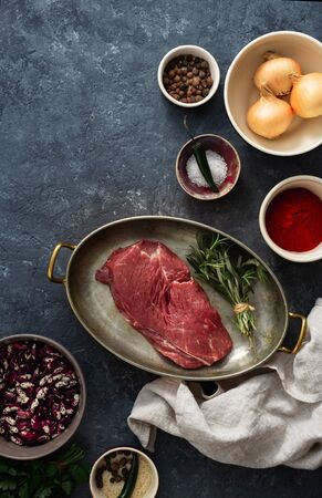 Raw beef meat with ingredients for cooking healthy food. Uncooked  beef meat with herbs, spices and beans top viewの写真素材