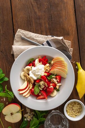 Fresh fruit salad on a wooden background top view. Healthy food plateの写真素材