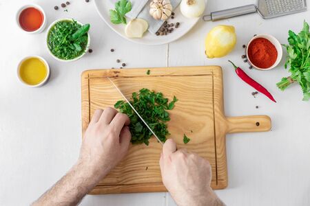 Man hands cooking above green Chimichurri or Chimmichurri salsa or sauce on white wooden tableの写真素材