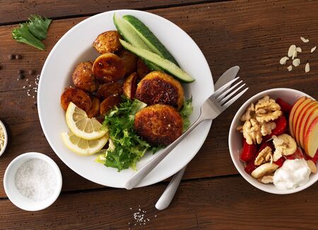 Dinner table with plate food. Fresh vegetarian cutlets with new potatoes and salad top viewの写真素材