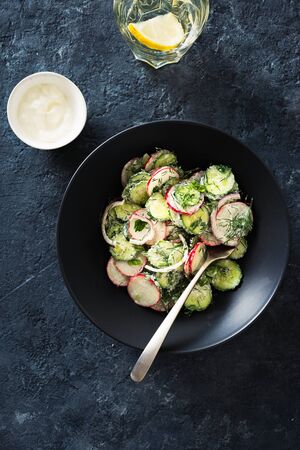 Bowl summer salad with radishes, cucumber and yogurt top view. Tasty and healthy foodの写真素材