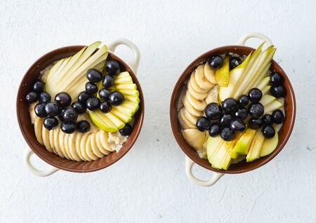 Plate with oatmeal and pear, apple, blueberry, banana on a white background top view. Breakfast table conceptの写真素材