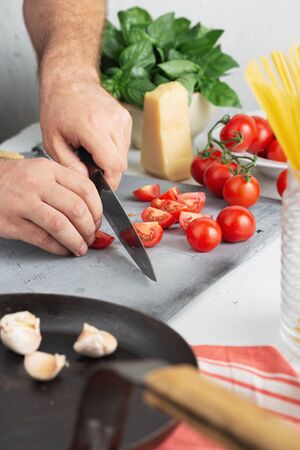 Chef cooking pasta with tomatoes in the kitchenの写真素材