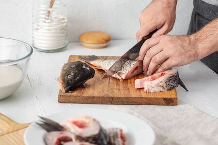 Man prepares carp river fish in home kitchen. Cooking healthy and diet foodの写真素材