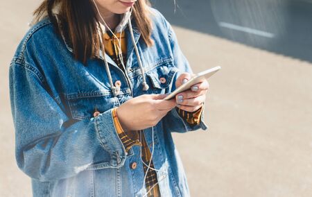 Happy young woman using social media on their smartphones walking down a city street