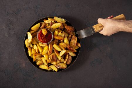 Male hands holding a pan with fresh fried potatoesの写真素材
