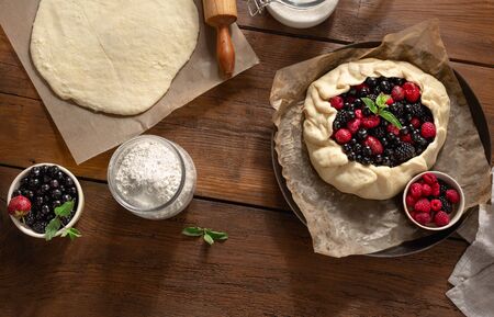 Raw pie cake with fruit strawberry, blueberry, blackberry and raspberry on a wooden table top view