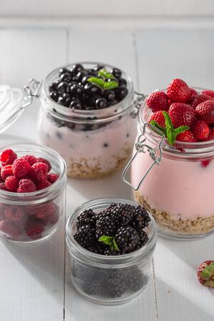 Healthy food breakfast. Granola yogurt with homemade strawberry, blueberry, blackberry and raspberry in glass jar in home kitchenの写真素材