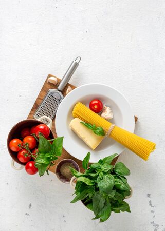 Raw Italian spaghetti with ingredients for cooking pasta on a whiteの写真素材
