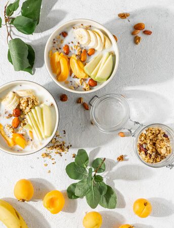Granola bowl with fruits, nuts, milk and peanut butter in bowl on a white background. Healthy breakfast cereal top viewの写真素材