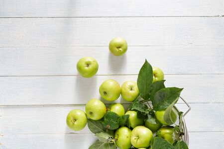 Pile of fresh green apple in colander on a wooden table top viewの写真素材