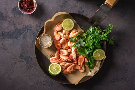 Raw prawns in a pan with ingredients for cooking on a dark background top viewの写真素材