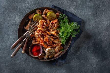 Fresh fried spiced shrimp in a frying pan on dark background top viewの写真素材